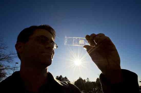 Sandia project lead Greg Nielson holds a solar cell test prototype with a microscale lens array fastened above it. Together, the cell and lens help create a concentrated photovoltaic unit.